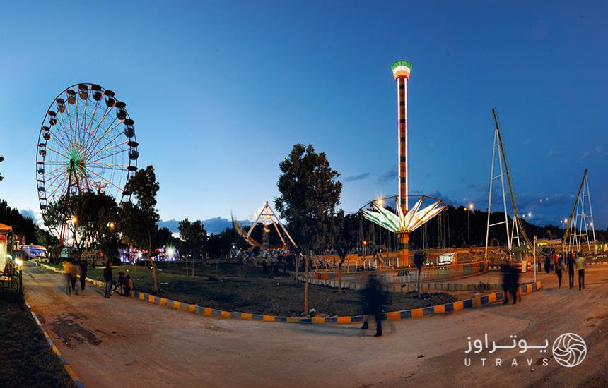 مجموعه پارک ارم تهران؛ تصویر پانورامیک از وسایل بازی و جمعیت مردم در پارک
